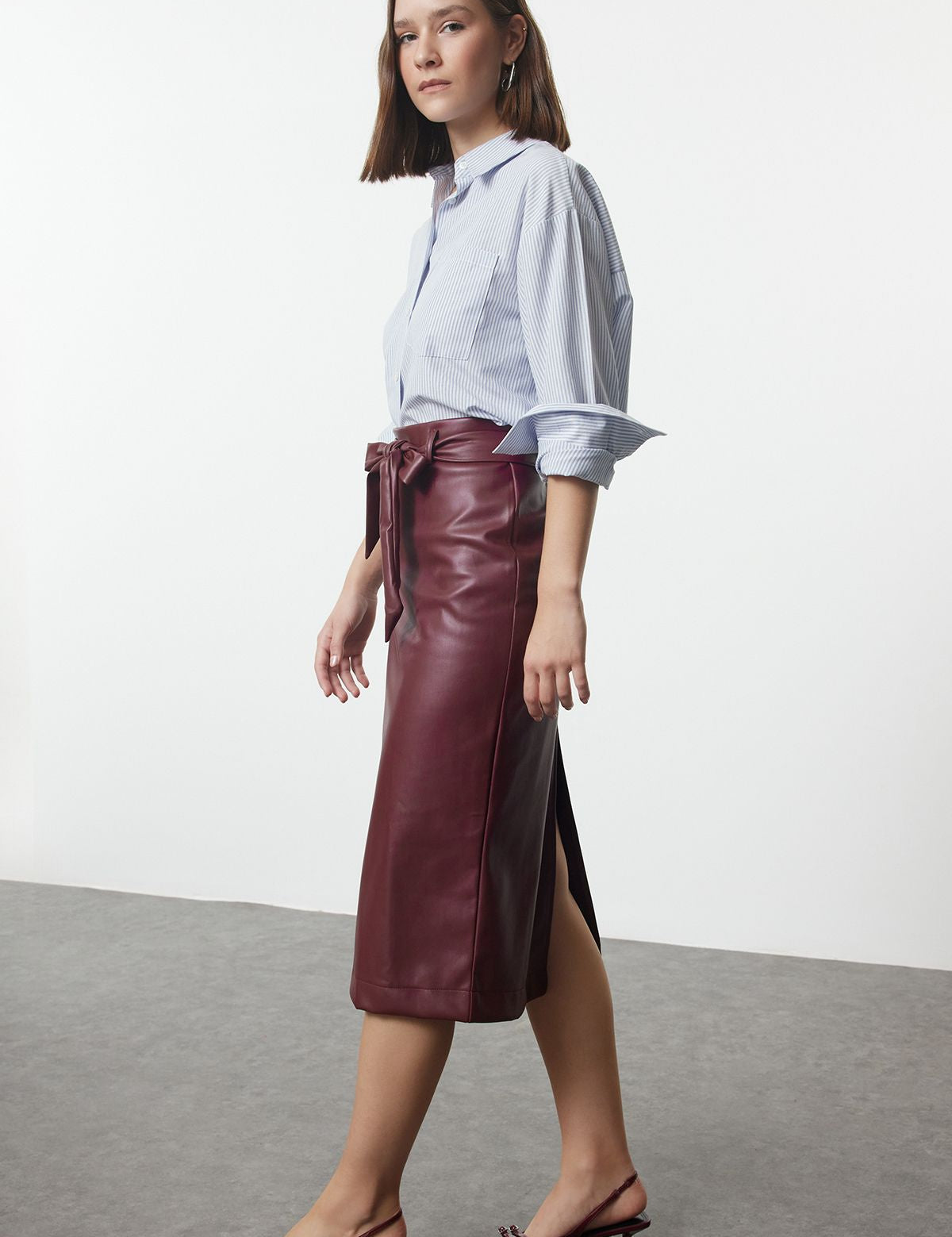 burgundy faux leather skirt, bow belt midi skirt, elegant leather-look skirt, women’s midi skirt, sophisticated faux leather skirt, high-waisted skirt, professional leather skirt, fashion faux leather skirt, trendy burgundy skirt, office wear skirt