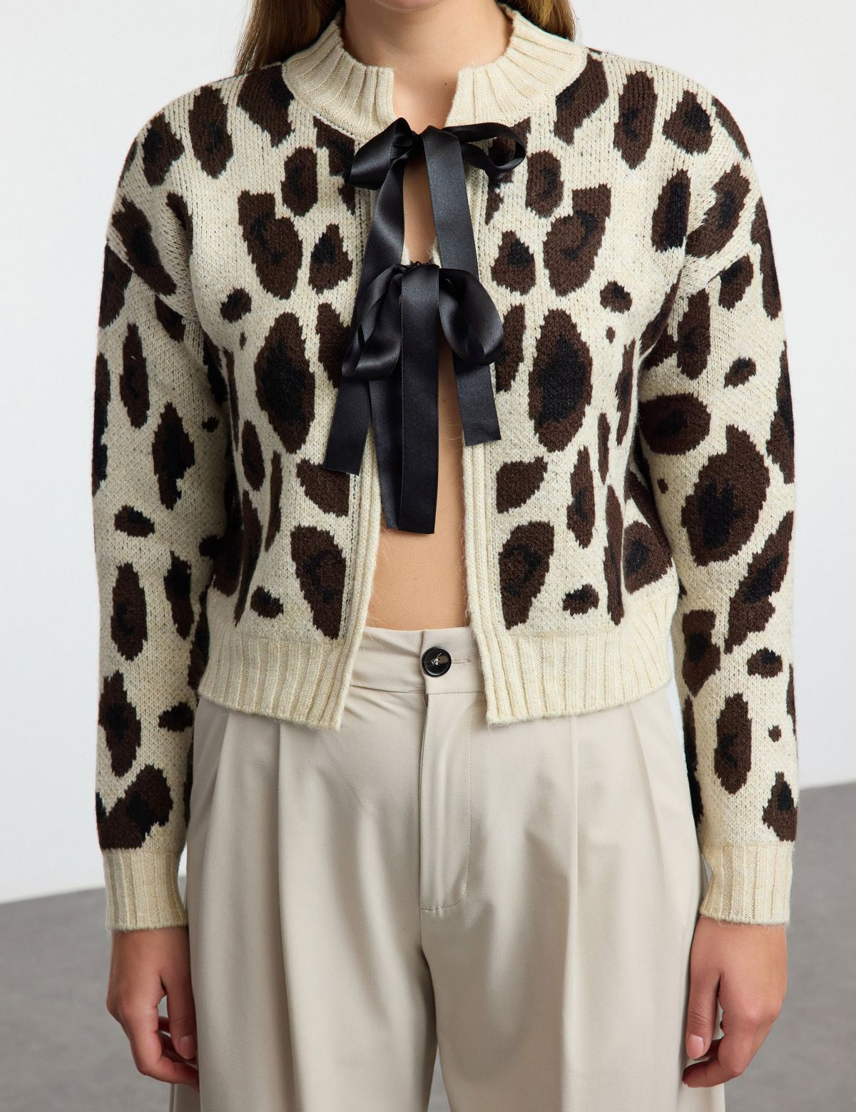 Shop this chic leopard print cardigan featuring a satin ribbon tie. Perfect for adding a statement touch to your wardrobe. Stylish, versatile, and on-trend knitwear!