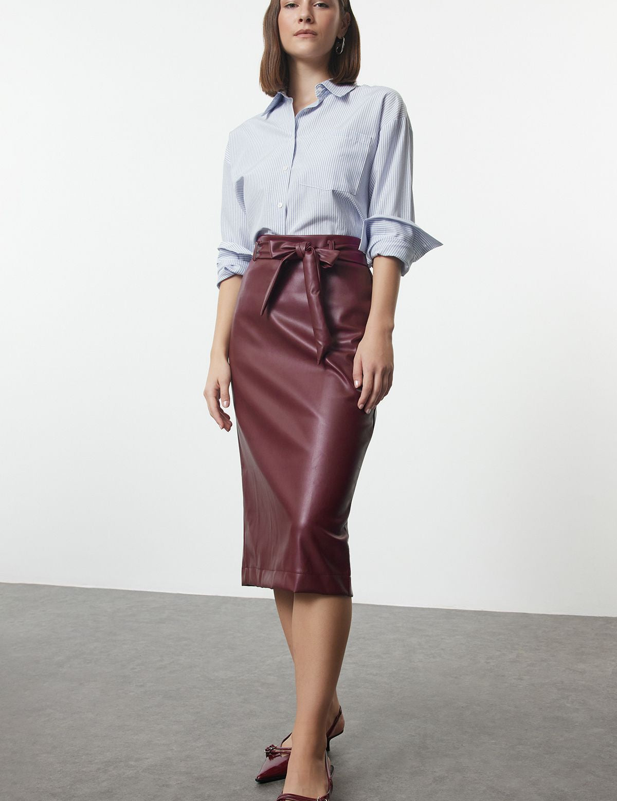 Upgrade your wardrobe with this elegant burgundy faux leather midi skirt featuring a chic bow belt. Perfect for professional or special occasions. Shop now!