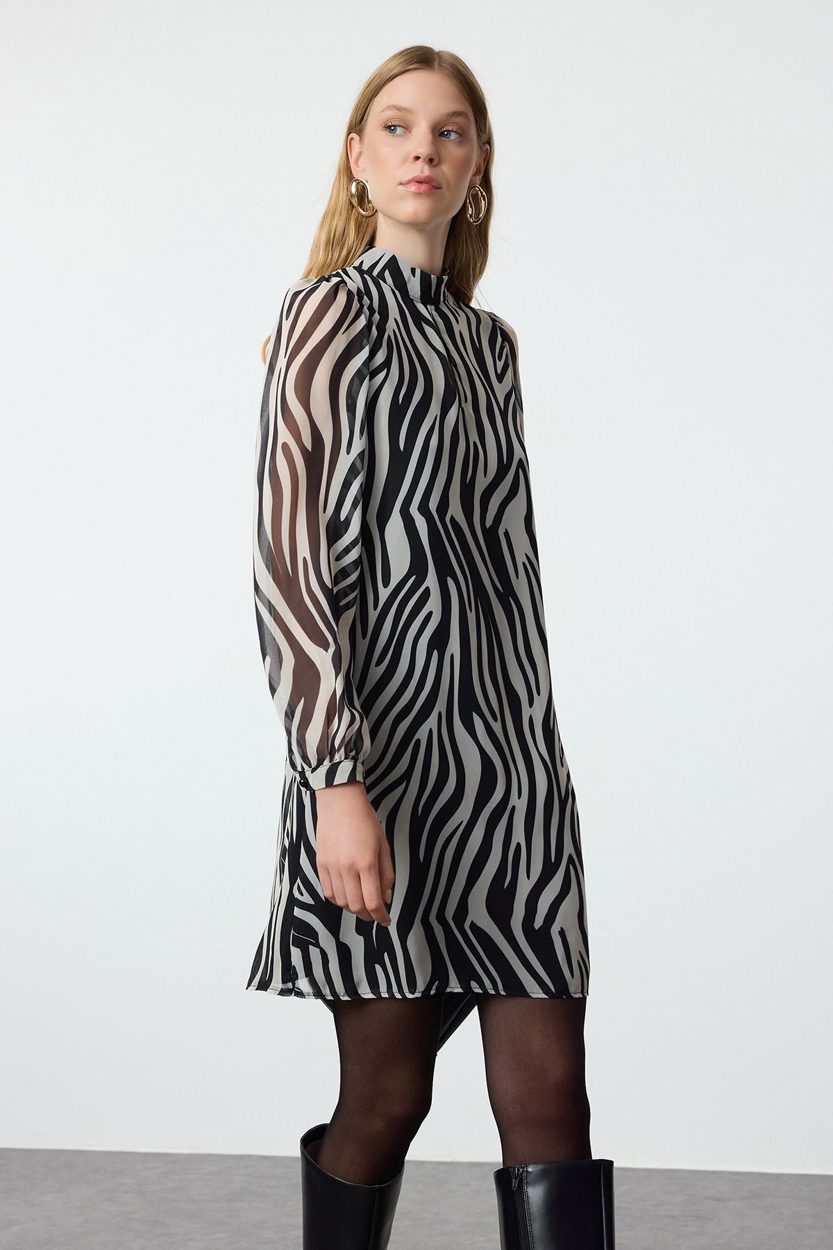 Turn heads with our Zebra Print Long Sleeve Shift Dress, featuring a bold black and white animal print, sheer sleeves, and a high neck. Perfect for day-to-night styling, this versatile dress offers a flattering fit for any occasion. Shop now for a standout look!