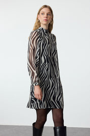 Turn heads with our Zebra Print Long Sleeve Shift Dress, featuring a bold black and white animal print, sheer sleeves, and a high neck. Perfect for day-to-night styling, this versatile dress offers a flattering fit for any occasion. Shop now for a standout look!